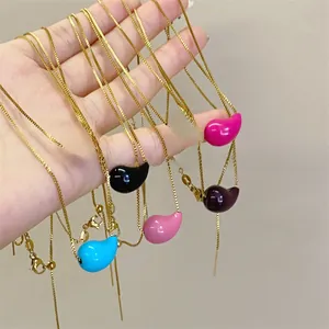 Macro shot of colorful enamel bean pendants on gold-plated chains in multiple colors