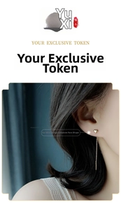Close-up of golden heart-shaped drop earrings with long elegant chain on model