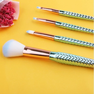 Detail of 4 mermaid makeup brushes with fish scale handles on yellow background