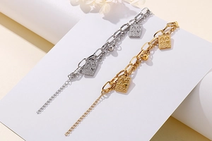 Detail of double-layer stainless steel chain bracelet with poker card pendants in gold and silver