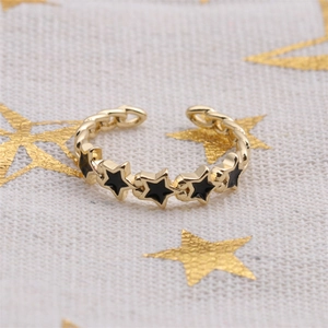 Detail shot of gold-plated star ring with black enamel inlay on star-patterned fabric