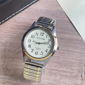 Detail of quartz watch dial with large Arabic numerals and bicolor elastic metal strap