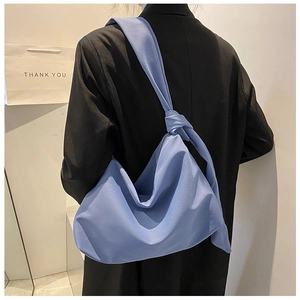 Rear view of a blue slouchy hobo bag featuring a decorative knot strap and large capacity