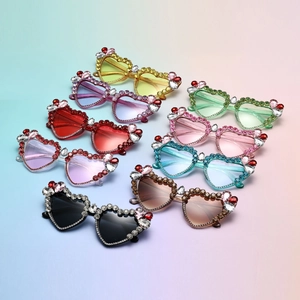 Flat lay view of colorful heart-shaped sunglasses with handmade rhinestone floral details