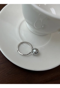 Primo piano dell'anello regolabile in argento S925 con perla grigia su piattino bianco