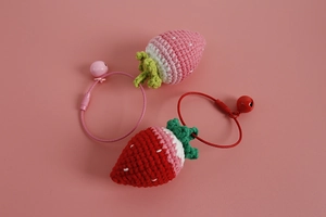 Detail shot of handmade crochet strawberry charms with bells and colorful wire rings