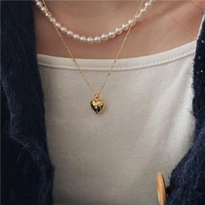 Close-up of layered golden heart pendant necklace and white round pearl necklace set