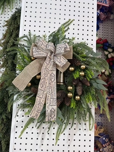 Detail of Christmas wreath with pine cones, golden baubles, bell and vintage ribbon bow