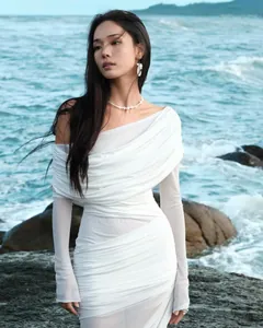 Close-up of white off-shoulder dress featuring draped texture and sheer mesh sleeves