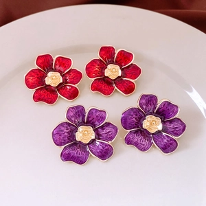 Detailed view of vintage flower earrings with red and purple enamel on a white plate