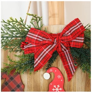 Detail of Christmas welcome sign with red buffalo plaid bow and realistic pine needles