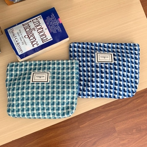 Détail d'un ensemble de deux trousses tissées bleues avec une étiquette en tissu