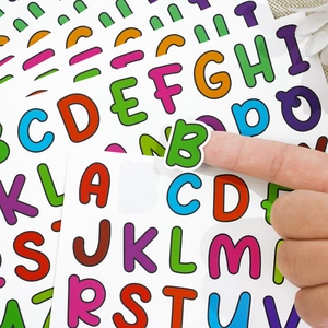 Close-up of peeling a colorful cartoon letter B sticker showing adhesive quality
