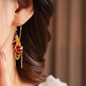 Detail of 18K gold-plated heart earrings with amber crystal pendants and tassels