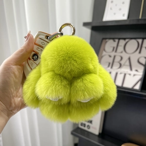 Detail of neon green plush rabbit keychain charm with soft faux fur and metal ring