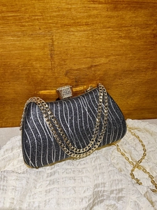 Elegant black shimmering evening clutch bag with silver wavy stripes and a gold chain strap