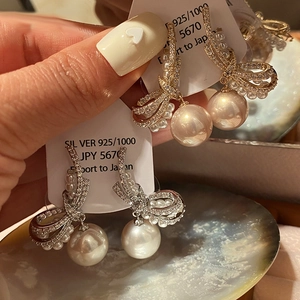 Macro view of 925 silver bow stud earrings with sparkling cubic zirconia and large round pearls
