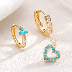 Detailed close-up of gold star and moon earring set with turquoise and white zircon accents