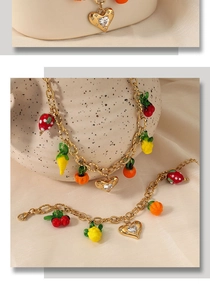 Close-up of gold fruit charm necklace and bracelet set with strawberry and lemon pendants