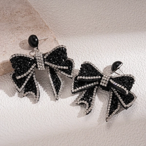 Gothic style black bow earrings with sparkling rhinestones on natural stone background