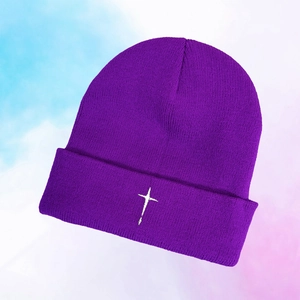 Close-up of purple knit beanie with white embroidered cross and soft texture
