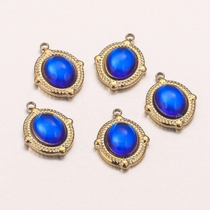 Detail of five gold-framed blue oval glass pendants on light pink gradient background