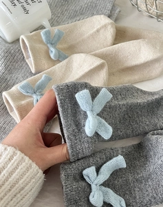 Detailed close-up of warm wool socks with light blue knit bows in beige and dark grey