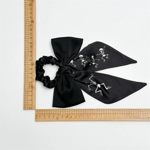 Black bow scrunchie with white skull print and long ribbons shown with measurement rulers