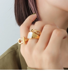 Detail of 18K gold-plated rings with white shell inlay and horseshoe clasp design
