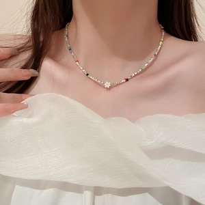 Collier ras du cou coloré avec pendentif fleur blanche porté par un mannequin femme