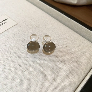 Macro shot of minimalist translucent brown and clear spherical earrings on fabric