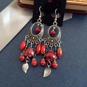 Detail of bohemian red tassel drop earrings with acrylic beads and hollow metal leaves