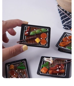 Nahaufnahme eines realistischen Mini-Harz-Grillteller-Modells zur Größenanzeige per Hand