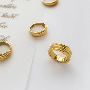 Detail view of four stacked gold rings with grooved textures and polished finishes