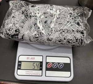 Dettaglio di un berretto in maglia da 54g in busta che mostra il peso reale sulla bilancia