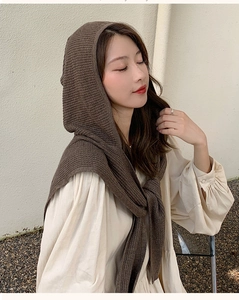 Detail of a brown knitted hooded scarf wrap shown on a model for a cozy winter style