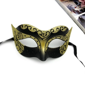 Detail of masquerade half-face mask with gold glitter patterns and black ribbon ties