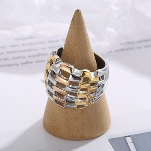 Detailed view of three-tone braided mesh rings in gold, rose gold and silver on wood stand