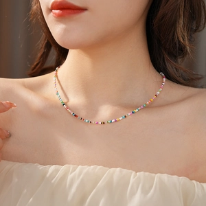 Close-up of a colorful glass beaded choker necklace worn on a model's collarbone