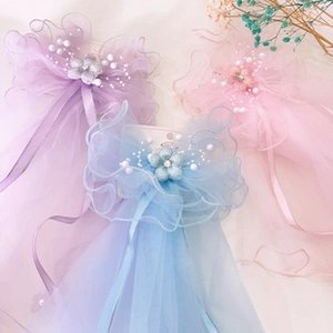Detailed view of tulle bow hair clips with pearls and flowers in purple, pink and blue