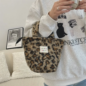 Detail of plush leopard print handbag with white woven brand label and black zipper