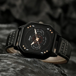 Close-up of a men's square quartz watch with black leather strap on a textured stone