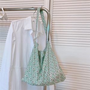 Detail of floral green cotton tote bag hanging on a rack in a bright natural setting