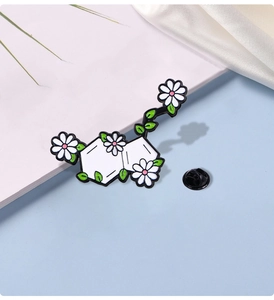 Detail of chemical molecule brooch featuring white daisies and green leaves on silk