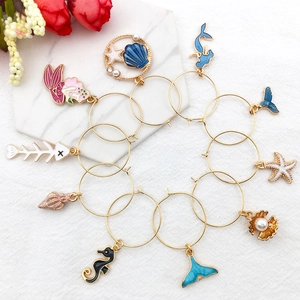 Nautical theme gold enamel wine glass charms with sea creatures charms on white cloth