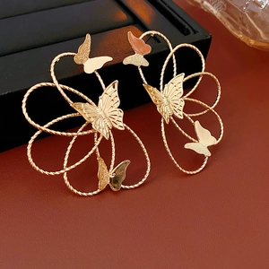 Detailed view of golden butterfly earrings with hollow woven texture on a black jewelry box