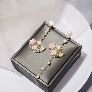 Detail of Chinese fan earrings with gold fringe, pearls and pink petals on display