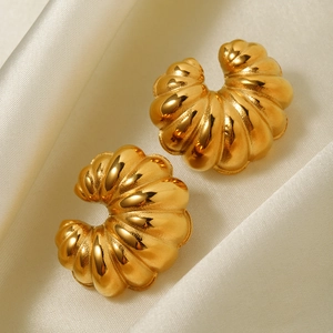 Macro detail of gold 18k croissant earrings on white satin fabric background