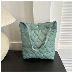 Detail view of mint green quilted tote bag with heart patterns and gold snap button