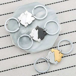 Three pairs of stainless steel rabbit keychains in yin-yang design on marble coaster
